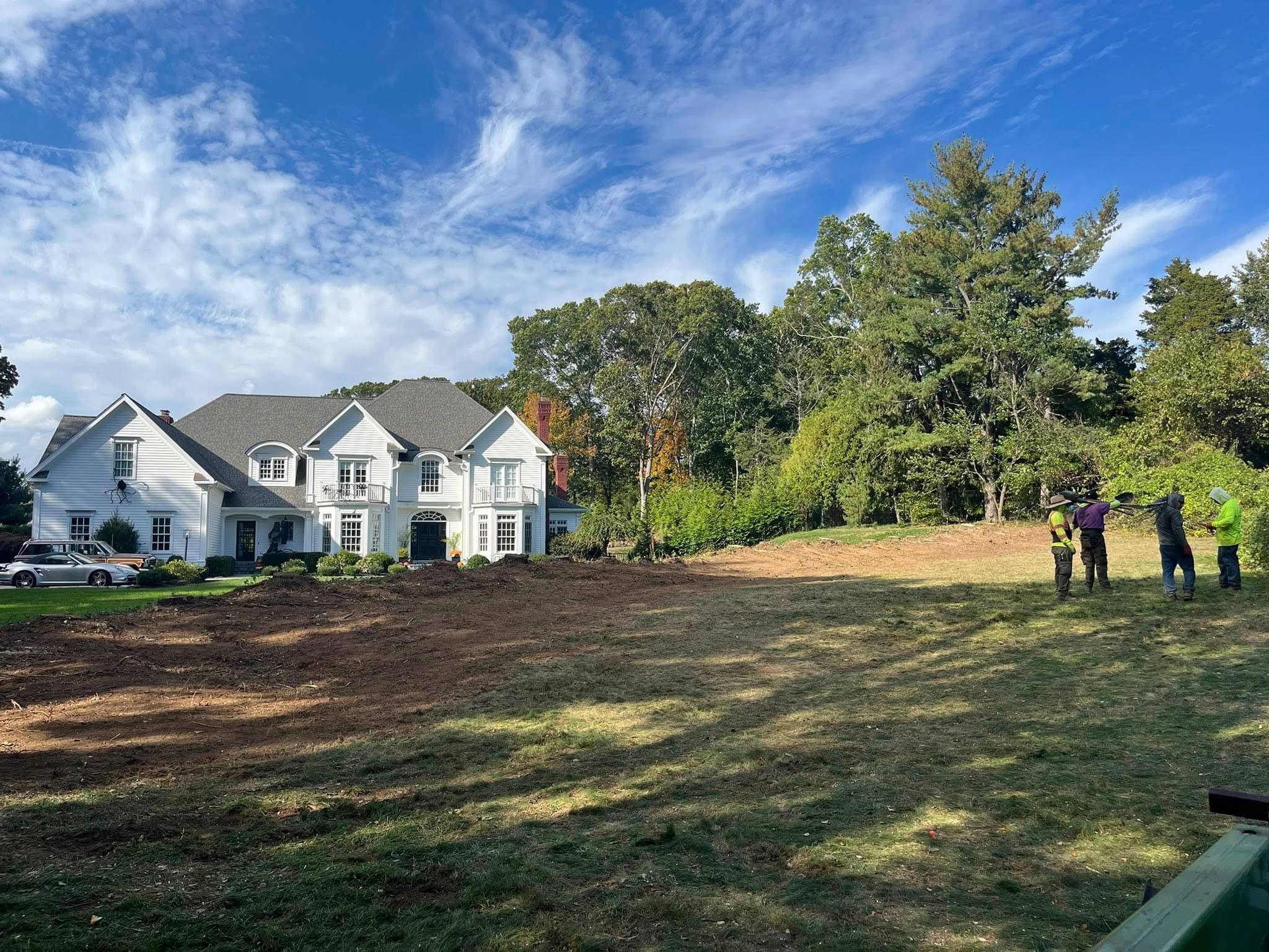 Professional landscape installation in progress with stone retaining wall construction at a residential property